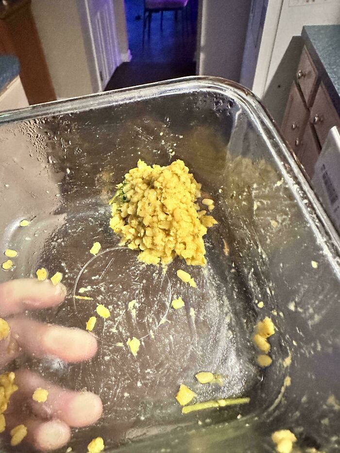 A hand reaching into an almost empty baking dish with leftover food, a glimpse into daily relationship struggles.