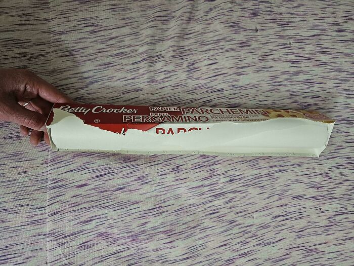 A hand holding a partially opened box of Betty Crocker parchment paper, a frustrating moment in relationships.