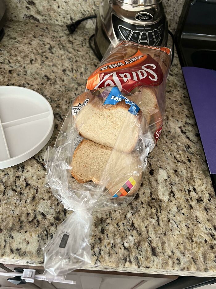 A loaf of Sara Lee Honey Wheat bread left open on a kitchen counter, a relatable struggle in shared living.