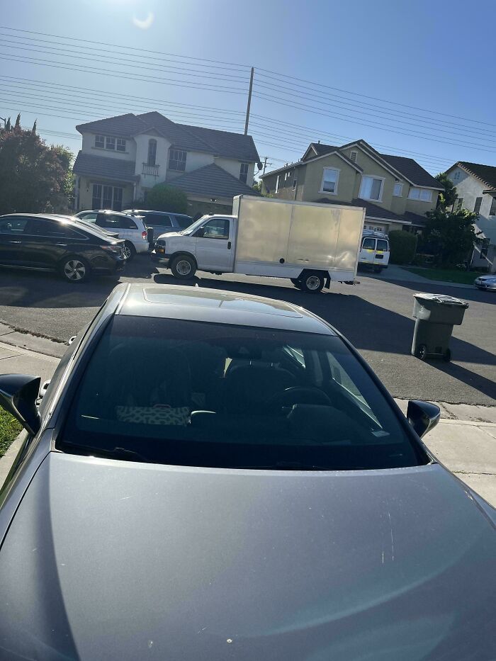 A large white delivery truck obstructing a residential street, reflecting poor parking by neighbors.