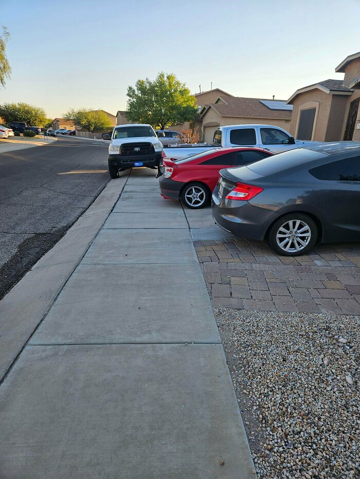 A white truck poorly parked on a sidewalk, obstructing pedestrian access, showing bad parking neighbors.