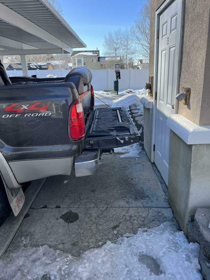 A pickup truck with its tailgate down blocking a doorway, illustrating inconsiderate parking by jerk neighbors.
