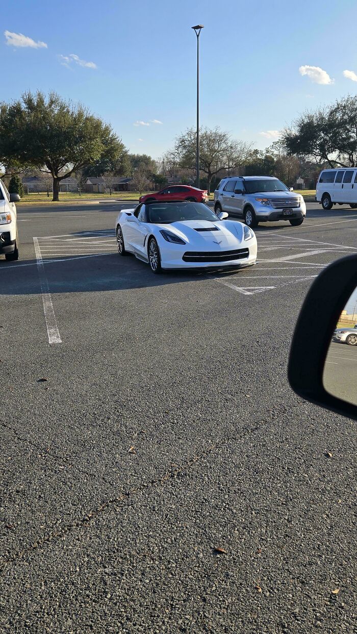 A white sports car parked diagonally, occupying multiple parking spaces, a prime example of jerk neighbors' parking.