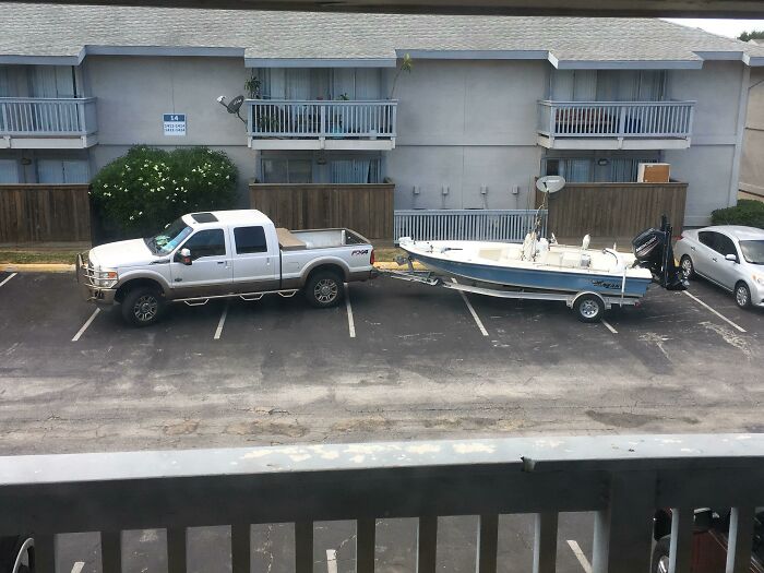 A large truck with a boat trailer taking up multiple parking spaces, showing a lack of common sense by jerk neighbors.