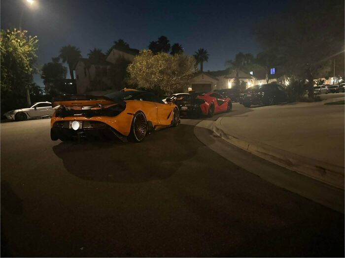 Luxury sports cars in an urgent parking lesson, parked closely together on a residential street at night.