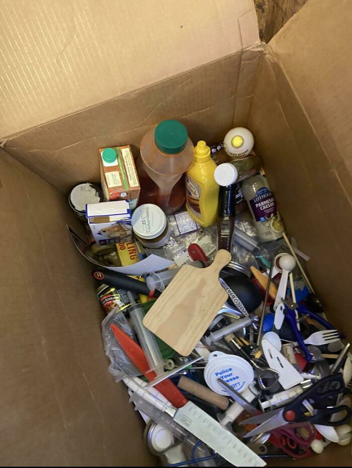 A cardboard box filled with various items, including food and kitchen utensils, highlighting a messy relationship scenario.