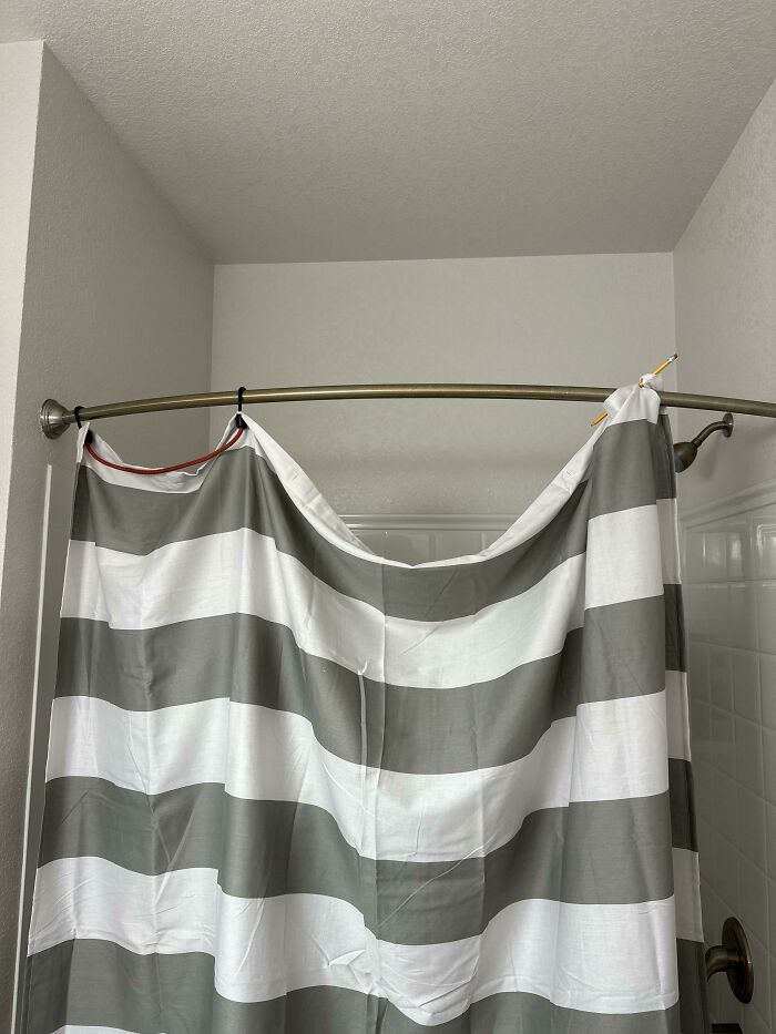 A shower curtain hung incorrectly with missing rings and a pencil, depicting a chaotic home life in relationships.