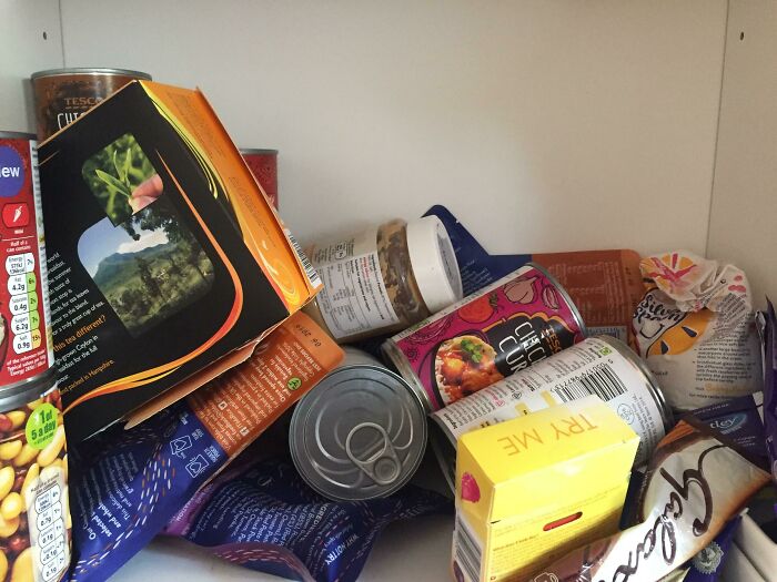 A messy pantry filled with various food items and cans, depicting a man in relationships