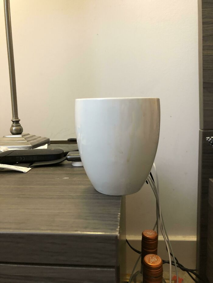 A white cup precariously balanced on the edge of a bedside table, showing a man in relationships