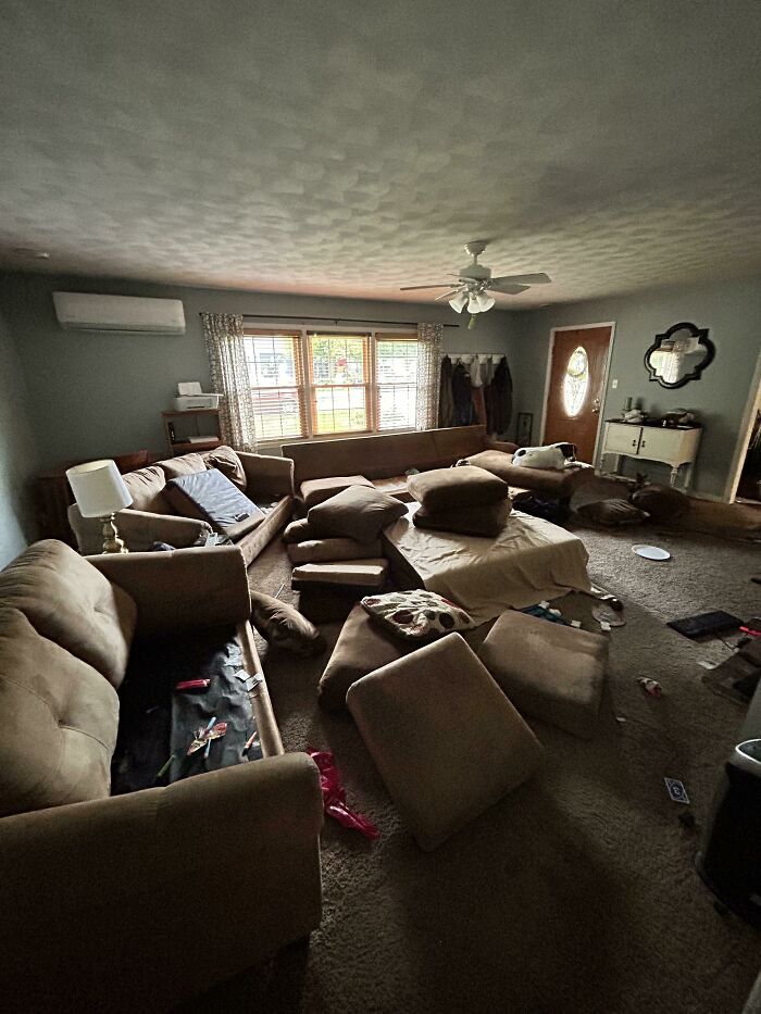 A chaotic living room with cushions and furniture scattered, reflecting a man in relationships