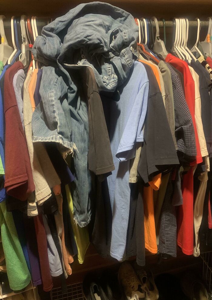 A messy closet with clothes piled on hangers, showing the appeal of becoming a cat lady.