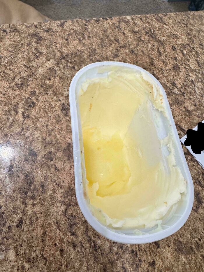 A partially used tub of butter on a countertop, suggesting a moment that makes a cat lady life appealing.