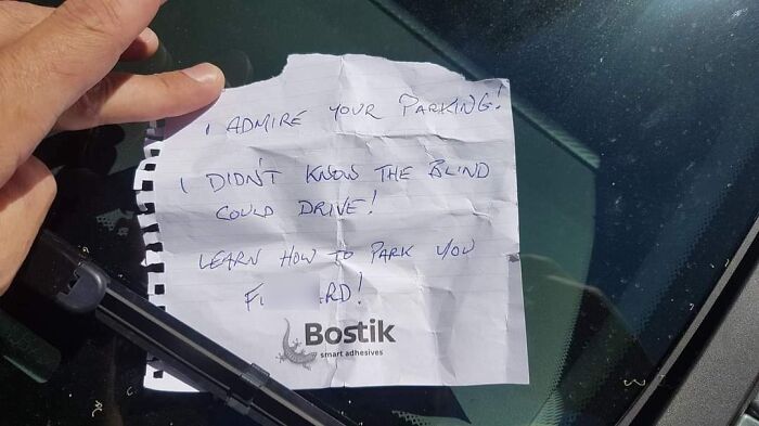 A harsh note on a car windshield criticizing bad parking, highlighting the frustration with jerk neighbors.