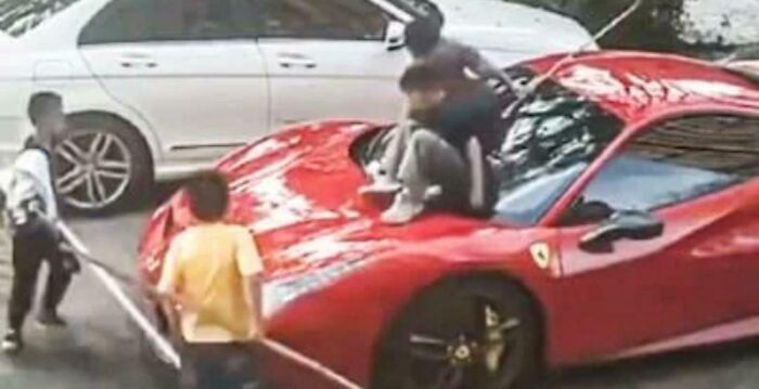 Kids playing on a red sports car, creating a challenging moment for parents.