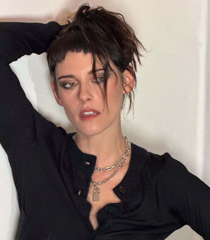 Close-up of Kristen Stewart with dark eye makeup, messy hair, and layered necklaces, highlighting her unsettling appearance.