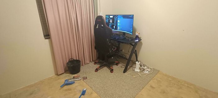 A simple and minimalist male living space featuring a gaming setup with a computer, chair, and basic decor.
