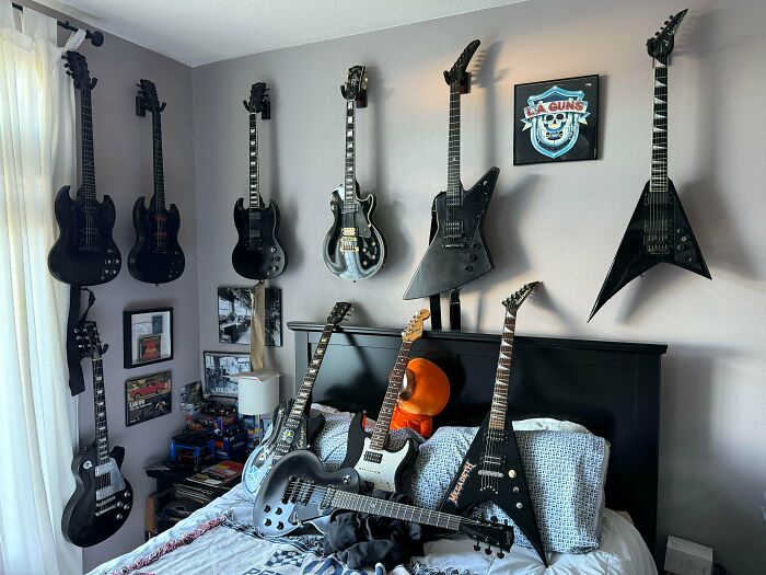 A male living space showcasing a collection of electric guitars hung neatly on a wall above a bed, creating a cool decor.