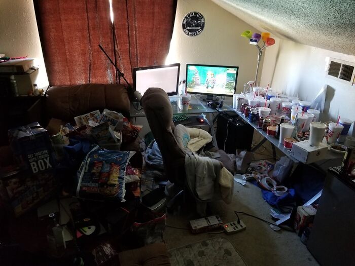 Male living spaces: An extremely cluttered gaming room with many cups and trash, showing how not to live.