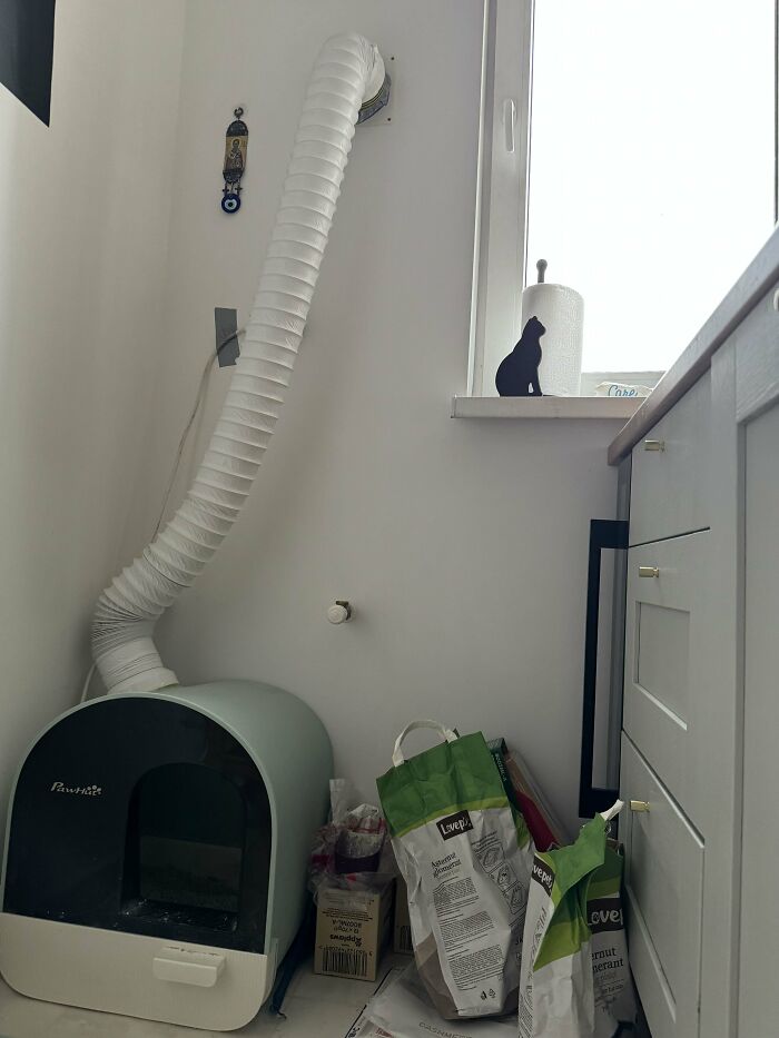 A white wall with a cat litter box with a ventilation pipe, part of a brilliant DIY home project.