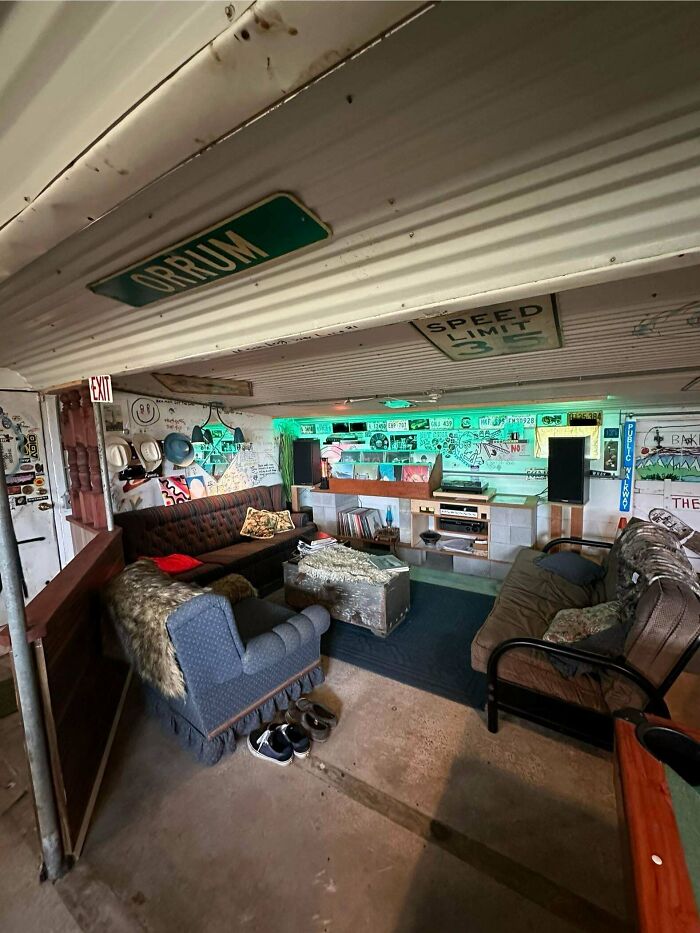 A unique male living space in what appears to be a repurposed container, featuring sofas, neon lighting, and quirky decor.