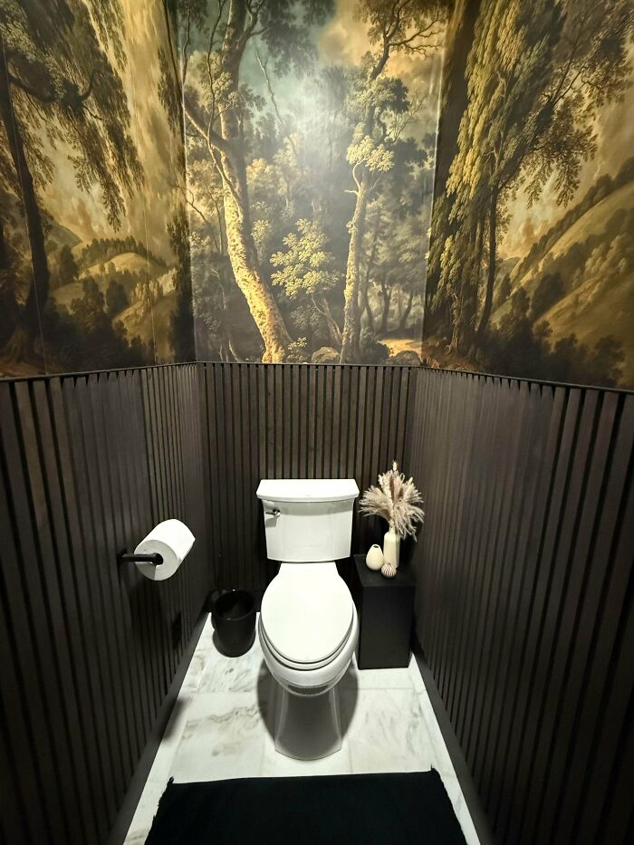 Powder room with dark wood paneling and forest mural, a brilliant DIY home project.