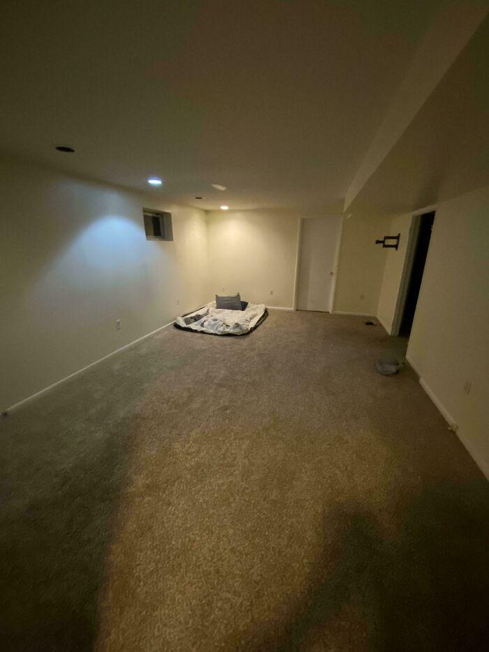 An empty male living space with a mattress on the floor, indicating a new or temporary setup.
