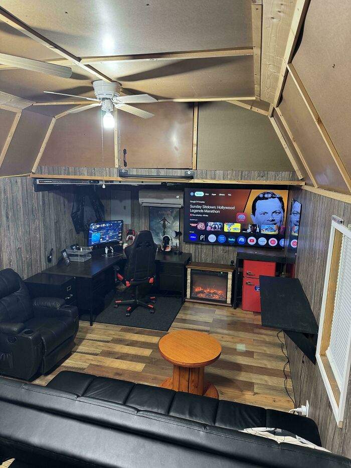 A cozy male living space featuring a large TV, computer setup, and seating, designed for entertainment.