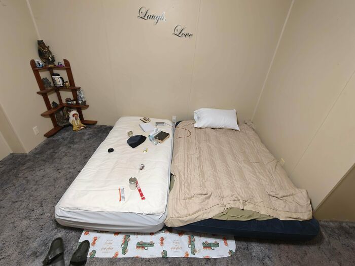Two mattresses on the floor in a room, one with clutter, depicting a humble male living space.