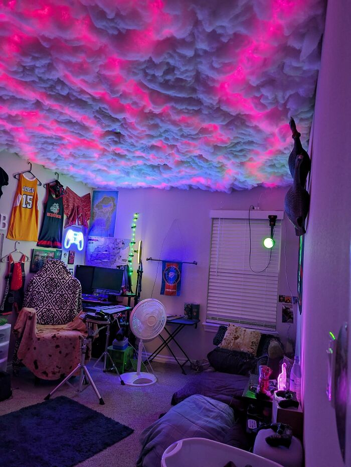 A bedroom with a ceiling decorated to resemble clouds illuminated by colorful lights, a brilliant DIY home project.
