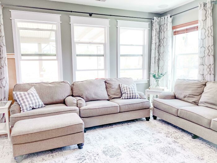 A cozy living room featuring DIY home projects with a budget-friendly sofa, ottoman, and patterned rug.