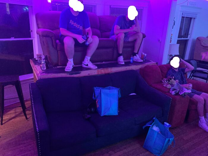 A male living space with multiple couches, men sitting, and purple lighting, showing inspiration.