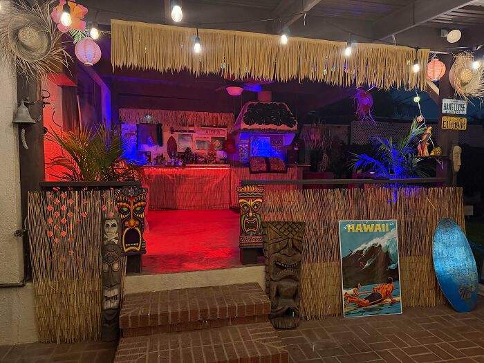 Lively DIY home project of a tiki-themed patio with bamboo decor, colorful lights, and statues, proving budget transformation.