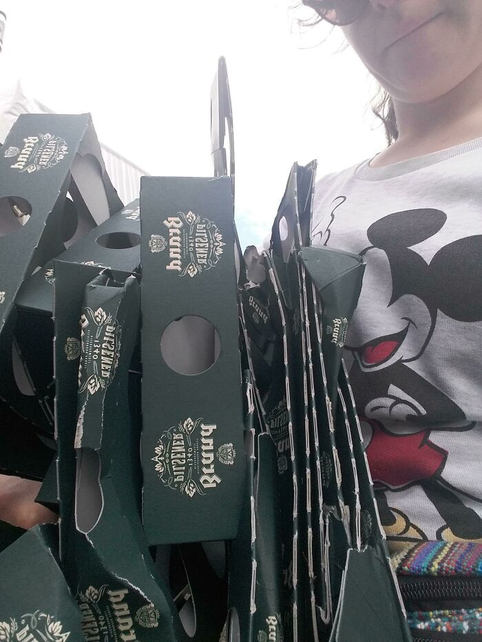 A person holds a large stack of flattened cardboard, demonstrating being an influencer for reducing trash.