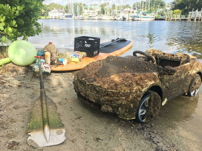 A dirty child's car and various trash items polluting a body of water, showing trash taking over the world.