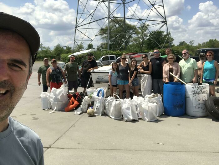 A group of people standing next to many bags of collected trash, showcasing efforts to reduce trash taking over the world.
