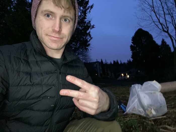 A man poses with collected trash, influencing others to take care of the world.