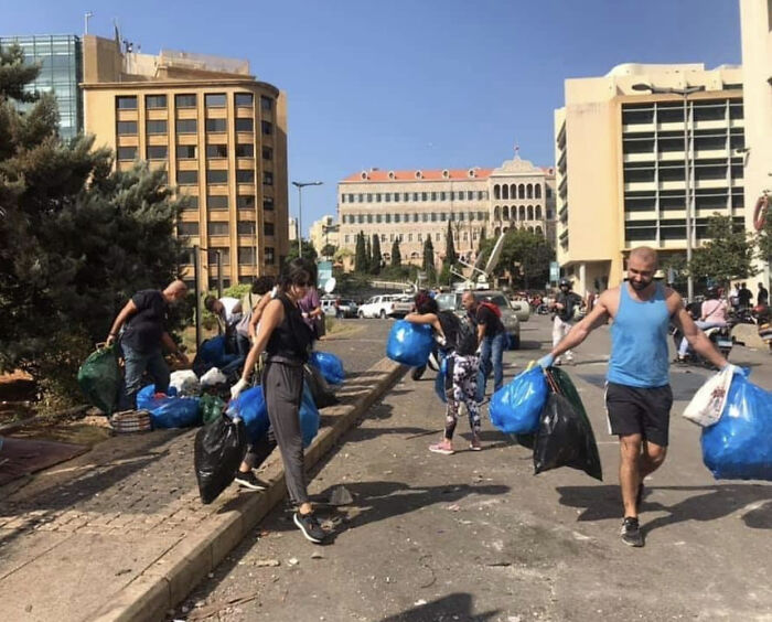 Volunteers carrying bags of collected trash on a city street, showcasing people cleaning up the world.