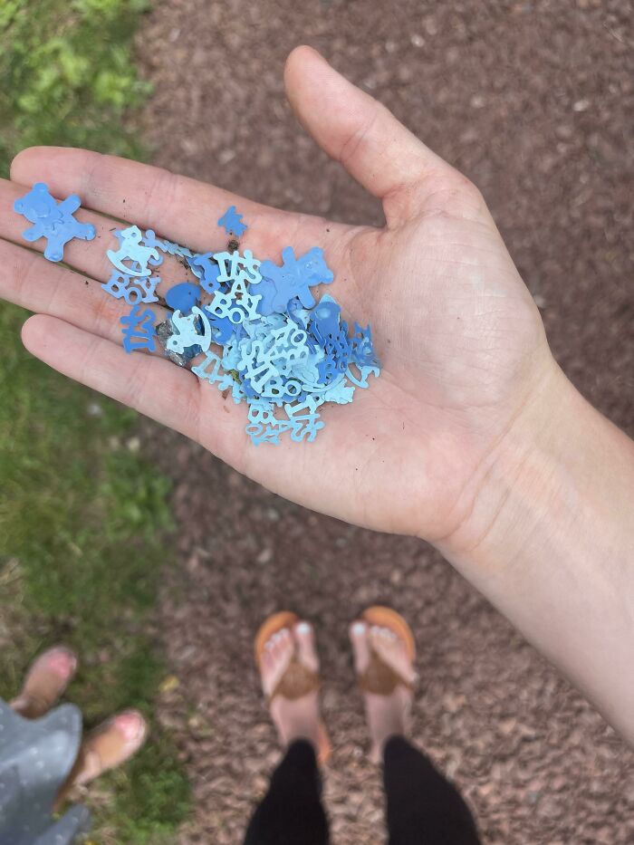 A person holding small blue plastic pieces in their hand, representing the tiny bits of trash taking over.