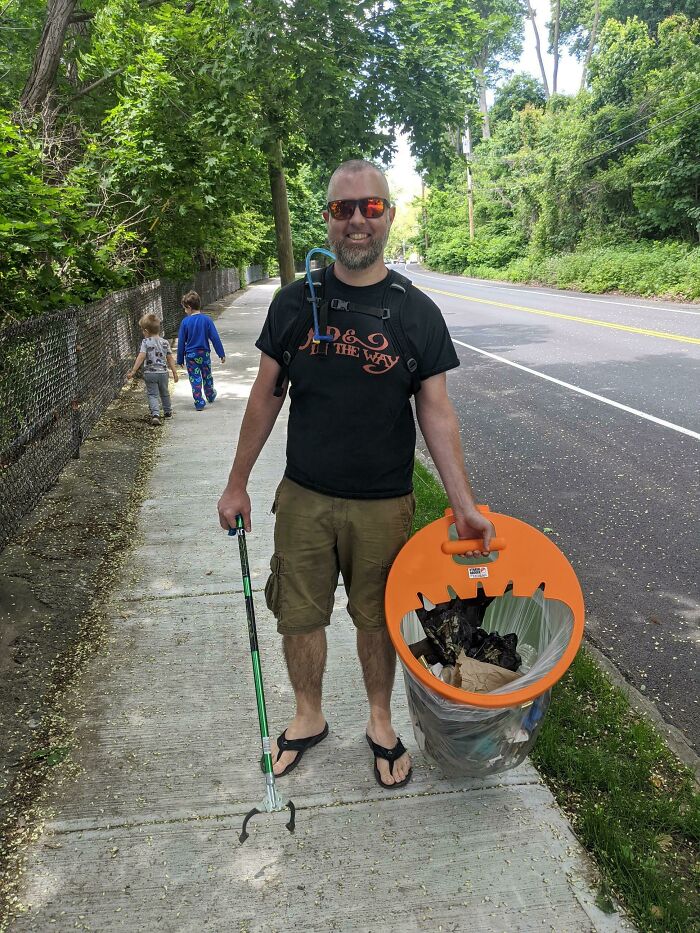 A man holding a trash grabber and a full trash bin, demonstrating how people can be real influencers against trash.