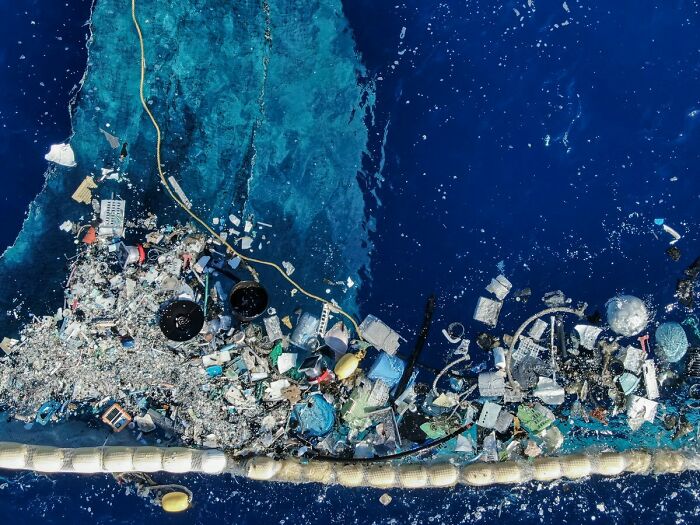 Aerial view of a large accumulation of trash floating in the ocean, demonstrating trash pollution.