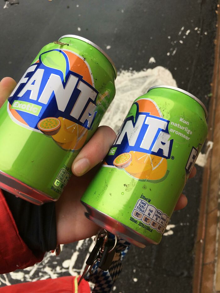 A hand holds two Fanta Exotic soda cans, representing everyday items that contribute to trash taking over the world.