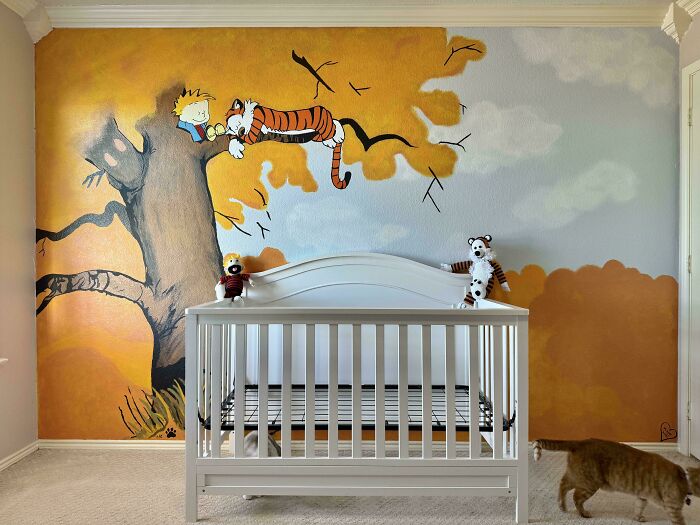A vibrant DIY home project showcasing a hand-painted Calvin and Hobbes mural above a white baby crib in a child's room.