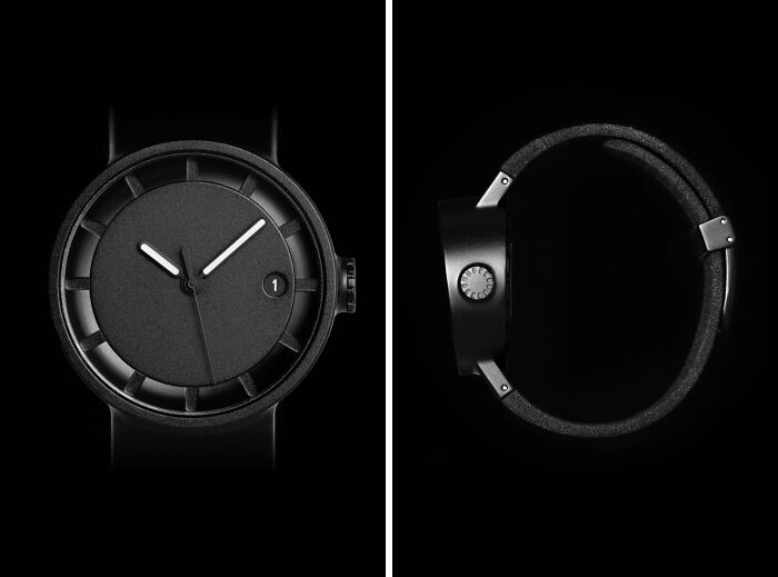 Close-up of a sleek black 3D printed watch, displaying its face and side profile against a dark background.