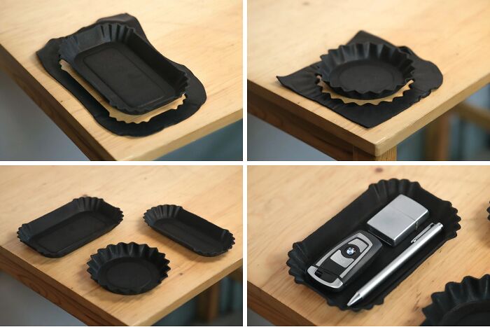 Collection of black 3D printed valet trays, holding keys, a lighter, and a pen on a wooden surface.