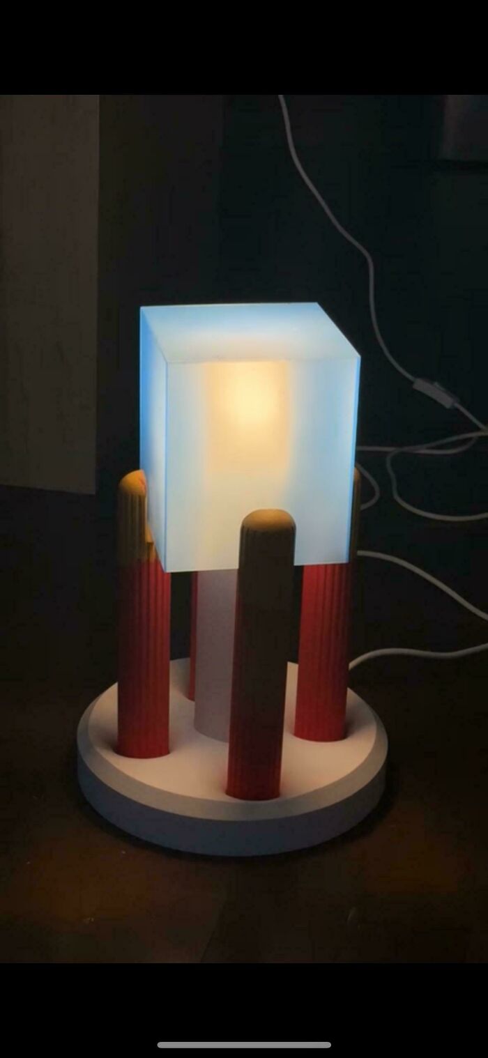 A uniquely designed lamp with a glowing blue cube and red pillars, showcasing brilliant 3D printers.
