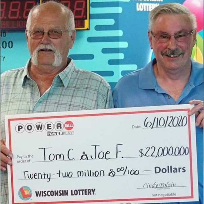 Two men smiling while holding a large check for $22,000,000.00 from the Wisconsin Lottery, showing how people got rich.