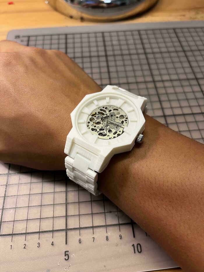 A white, intricate 3D printed watch with visible gears worn on a wrist, showcasing brilliant things made with 3D printers.