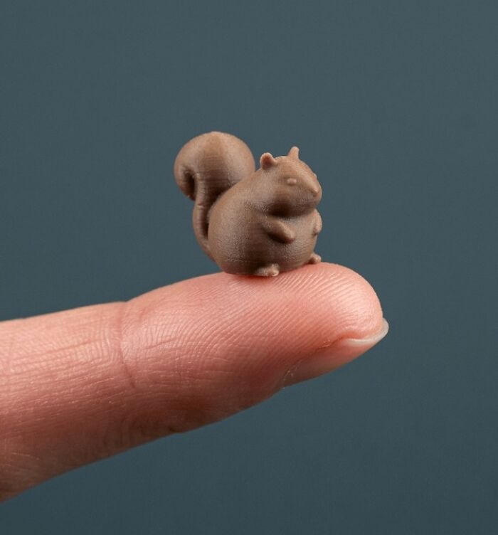 Tiny 3D printed squirrel figurine perched on a fingertip, demonstrating brilliant 3D printers capabilities.