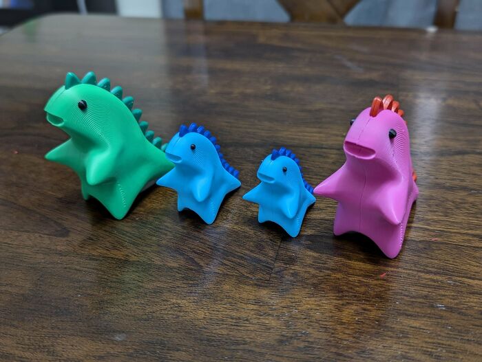 A group of brightly colored 3D printed dinosaur toys in green, blue, and pink, showing brilliant use of 3D printers.