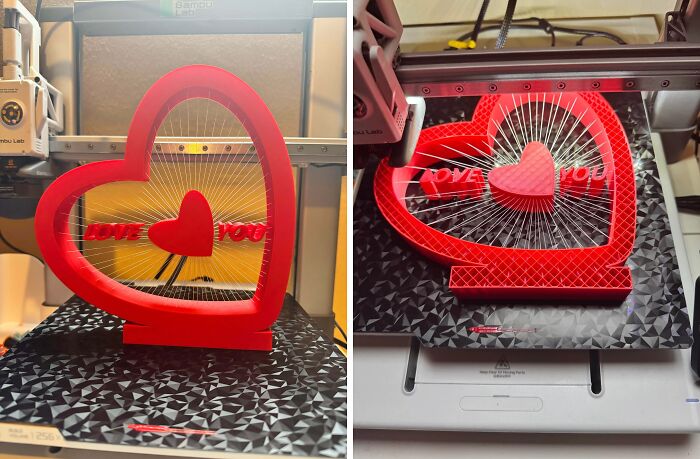 A red heart-shaped sculpture with the words LOVE YOU being created by 3D printers.